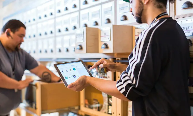 Dos personas revisando pedidos en una tablet dentro de una tienda